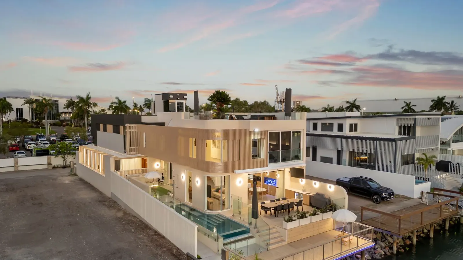 Casa La Mere at dusk seen from the water, pool terrace and living levels lit