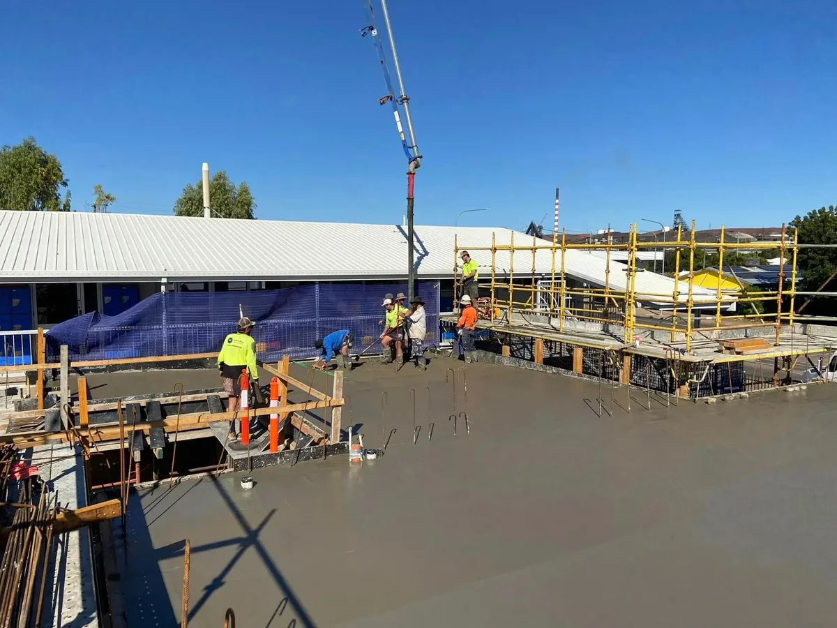 Concrete pour underway on a commercial slab with a crane and site crew