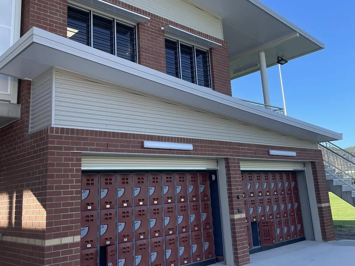 Two-storey school building in face brick with banks of student lockers under the walkway